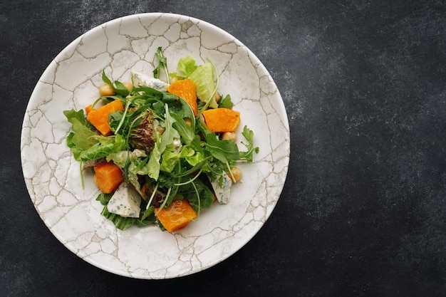 Salad with pumpkin cheese and herbs on a plate