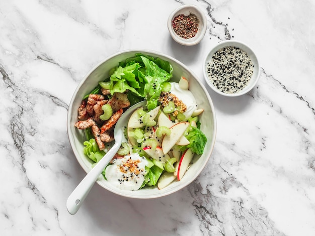 Salad with roasted turkey apple celery iceberg lettuce and greek yogurt dressing on a light marble background top view