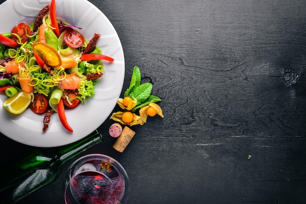 Salad with salmon and fresh vegetables and herbs Italian cuisine Top view On Wooden background