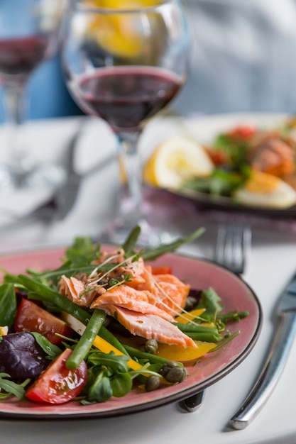 Salad with salmon and verdure in plate on table with blue chair background