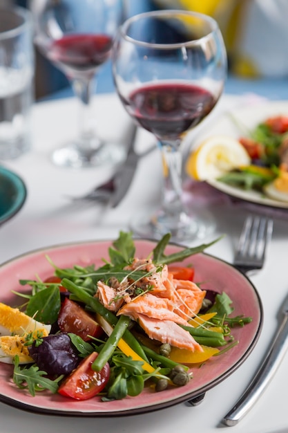 Salad with salmon and verdure in plate on table with blue chair background