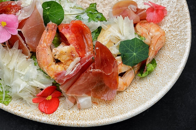 Salad with shrimp prosciutto and cheese on a plate