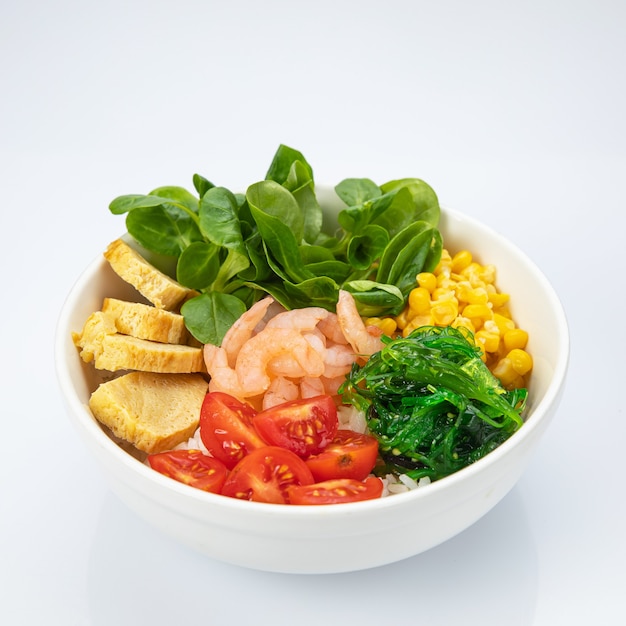 Salad with shrimp, tomatoes in a white plate on a white background