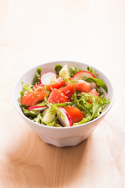 Salad with tomato, cucumber, radish, arugula and sesame seeds with olive oil