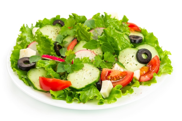 Salad with tomatoes cucumbers and radishes on a white plate