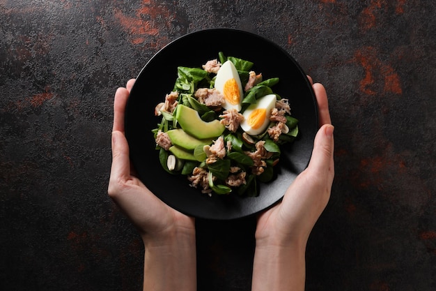 Salad with tuna on a dark table with a fork