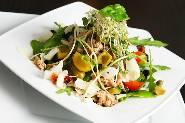 Salad with tuna on the plate over table