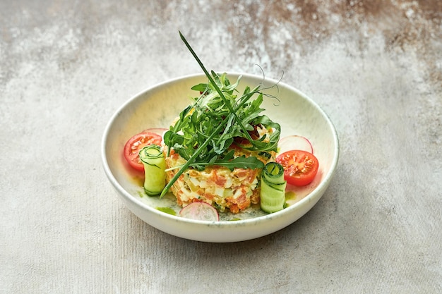 Salad with vegetables and salmon in a plate on a textured background. Close-up, selective focus