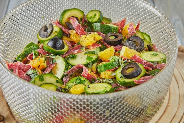 Salad with zucchini oranges and salami of French gourmet cuisine on wooden background