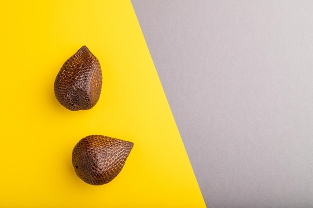 Salak or snake fruit on gray and yellow pastel background Top view copy space