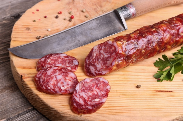 Salami and knife on a cutting board, top view