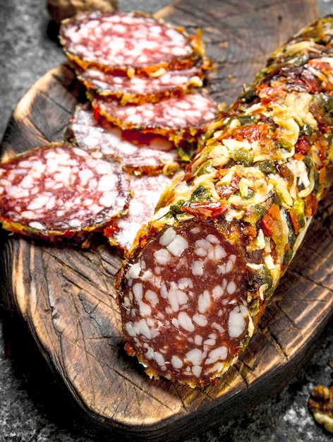 Salami with spices on a cutting board. On a rustic background.