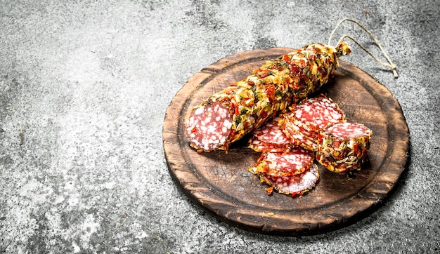 Salami with spices on a cutting board. On a rustic background