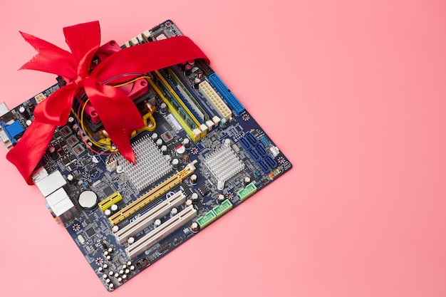 Sale of computer components, motherboard in red ribbon, on pink background, banner, copy space