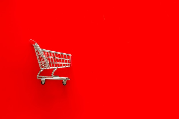 Sale concept with shopping trolley cart on red background