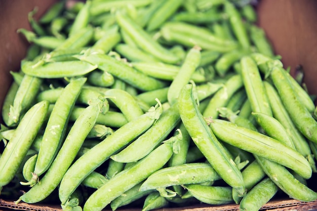 sale, harvest, food, vegetables and agriculture concept - close up of green peas in box at street market