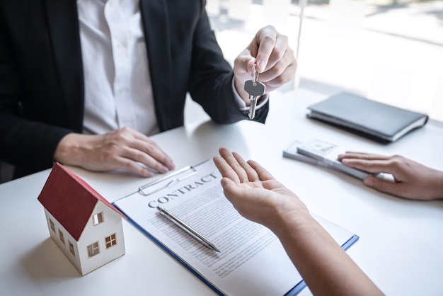 Sale purchase contract to buy a house, Real estate agent are presenting home loan and giving keys to customer after signing contract to buy house with approved property application form.