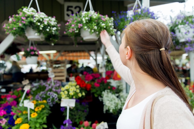 sale, shopping, gardening and people concept - close up of woman choosing flowers at street market