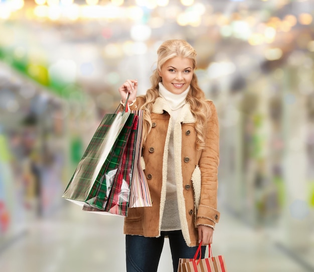 sale, shopping and mall concept - lovely woman with shopping bags at shopping mall