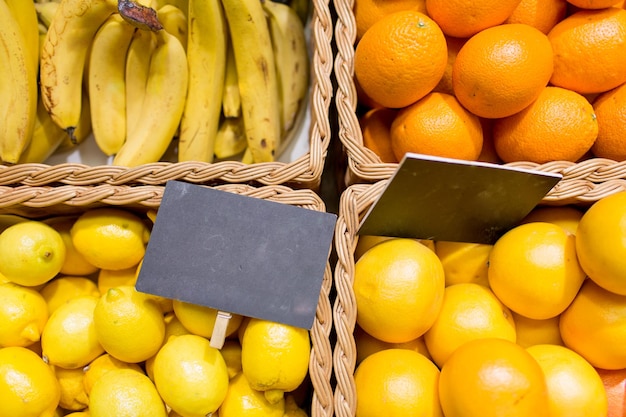 sale, shopping, vitamin c and eco food concept - ripe fruits in baskets with nameplates at grocery market