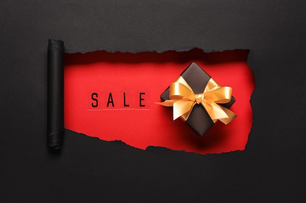 SALE text on red hole background with black gift box and golden bow. Shopping Discount promotion.