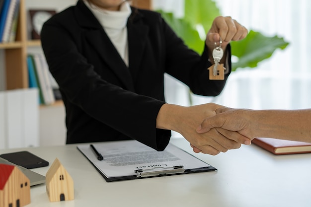 The sales representative shake hands and delivering the keys to the new homeowners