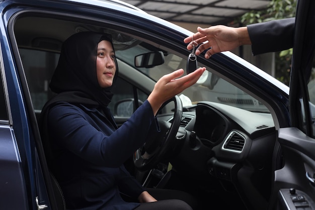 Salesman gives car keys to muslim woman client after successful retail deal in dealership centre