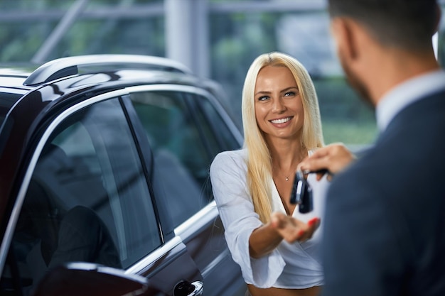 Salesman giving keys from new car to female customer