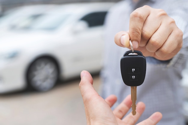 The salesman is delivering the new car keys to the customer at the showroom.