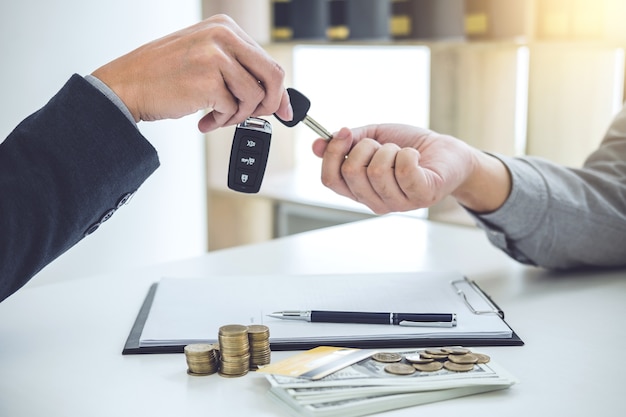 Salesman send key to customer after good deal agreement, successful car loan contract