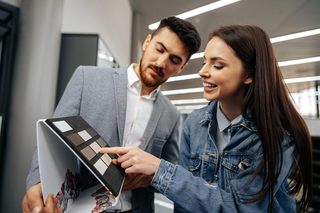 Salesman shows color swatches to lady customer for new kitchen furniture