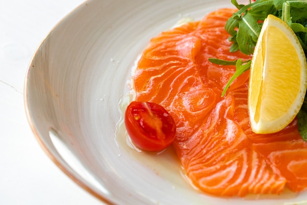 Salmon carpaccio served with lemon and arugula