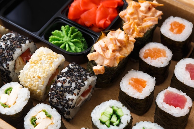 Salmon and cucumber sushi rolls with soy, ginger and wasabi. Asian food restaurant delivery, closeup of platter set on wooden background