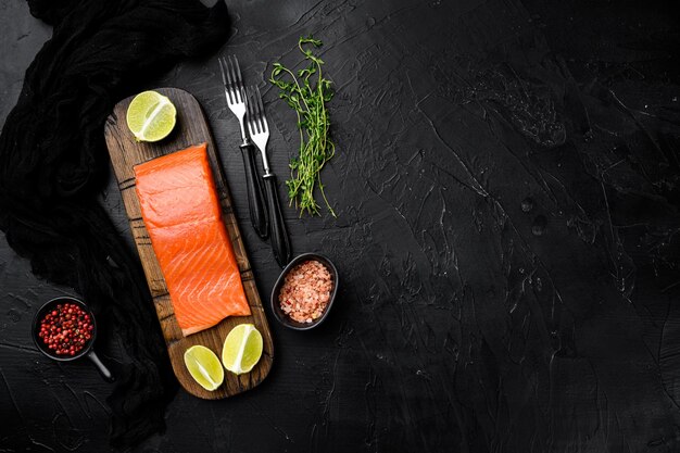 Salmon fillet fish with herbs on black dark stone table background top view flat lay with copy space for text