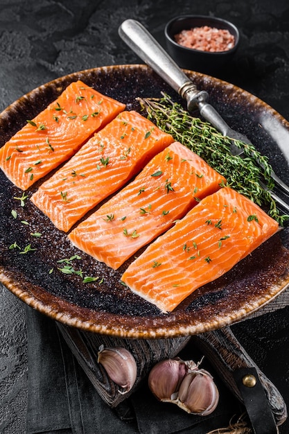 Salmon fillet steaks raw fish with thyme and herbs Black background Top view