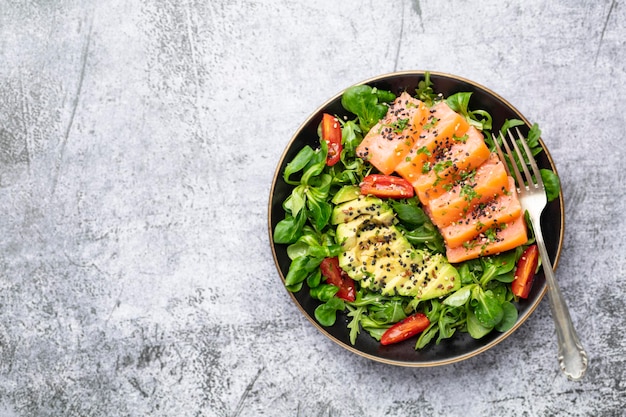 Salmon fish fillet with fresh salad, avocado top view.