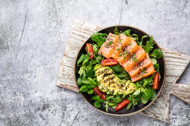 Salmon fish fillet with fresh salad, avocado top view.