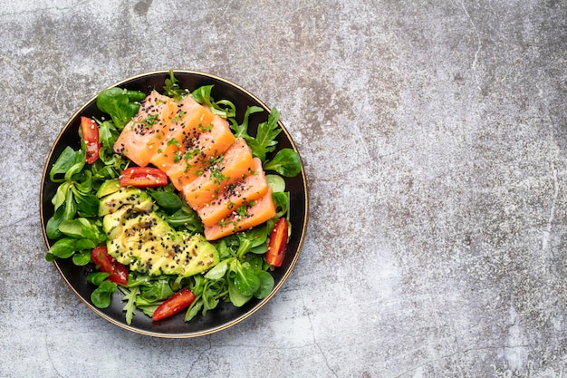 Salmon fish fillet with fresh salad avocado top view