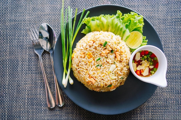 Photo salmon fried rice in black plate with spoon and fork