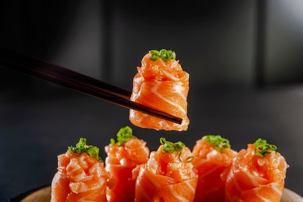 Salmon Jhow sushi on chopsticks in a black background Closeup