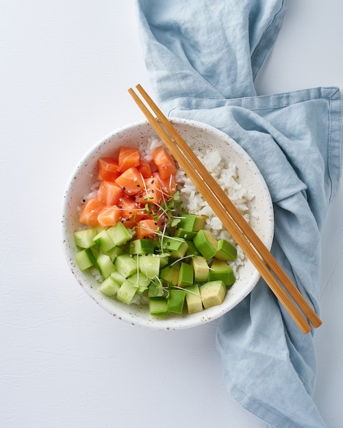 Salmon poke bowl with fresh fish, rice, cucumber, avocado with black and white sesame