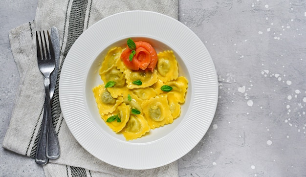 Salmon ravioli traditional Italian food with fresh basil in a white plate on a grey stone table. Recipe Italian food. food flat lay