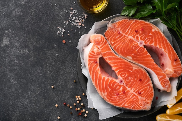 Salmon Raw salmon steak Fresh raw salmon fish with cooking ingredients herbs and lemon prepared for grilled baking on black background Healthy food Top view Copy space