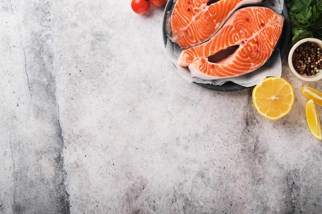 Salmon Raw salmon steak Fresh raw salmon fish with cooking ingredients herbs and lemon prepared for grilled baking on light grey background Healthy food Top view Copy space