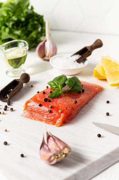 Salmon Raw trout and red fish steak is served with herbs lemon and olive oil on a white stone board Healthy Eating Concept