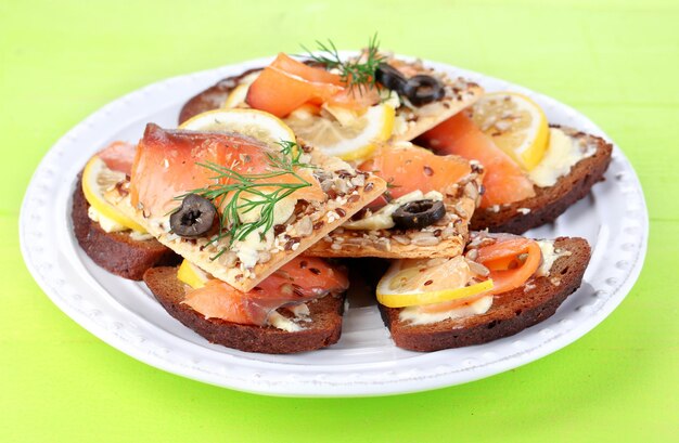 Salmon sandwiches on plate on wooden table closeup