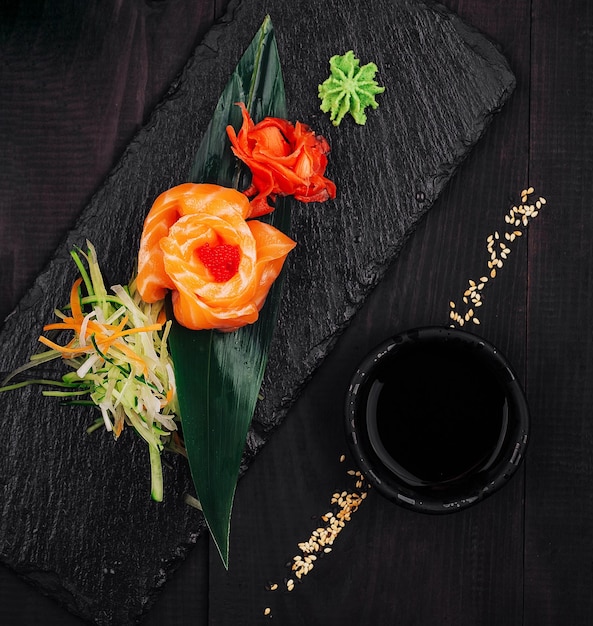 Photo salmon sashimi rose served on slate with wasabi and ginger on dark wooden table