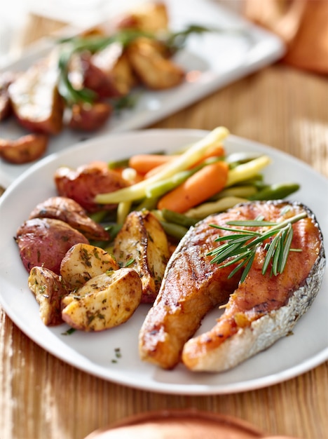 Salmon steak dinner with herbs and roasted potatoes.