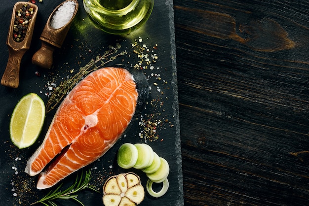 Salmon steak prepared for frying with ingredients on a dark background