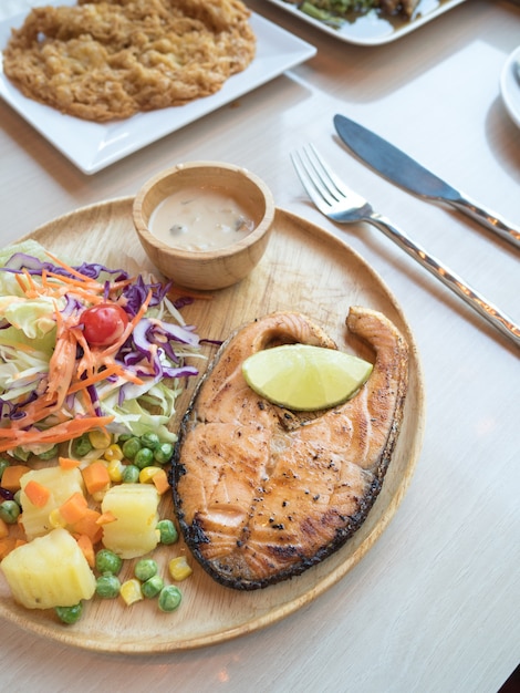 salmon steak on wooden plate on vintage table at natural restaurant 